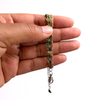 Hand holding a colourful bracelet in pale gold with rainbow bunting on a plain background.