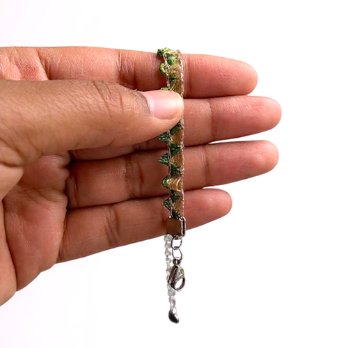 Hand holding a colourful bracelet in pale gold with rainbow bunting on a plain background.