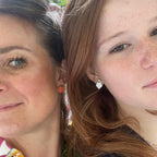 Close-up of two women wearing Autumn themed earrings - one with handmade orange pumpkin stud earrings and the other wearing handmade white ghost stud earrings.