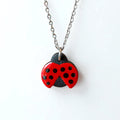 Necklace with a handmade ladybird pendant on silver chain with a white background.