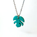 Necklace with a handmade green monstera leaf pendant on silver chain with a white background.