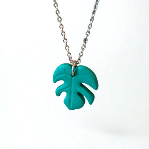 Necklace with a handmade green monstera leaf pendant on silver chain with a white background.