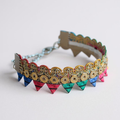 Colourful decorative bracelet with rainbow bunting and gold sequins on a plain background.