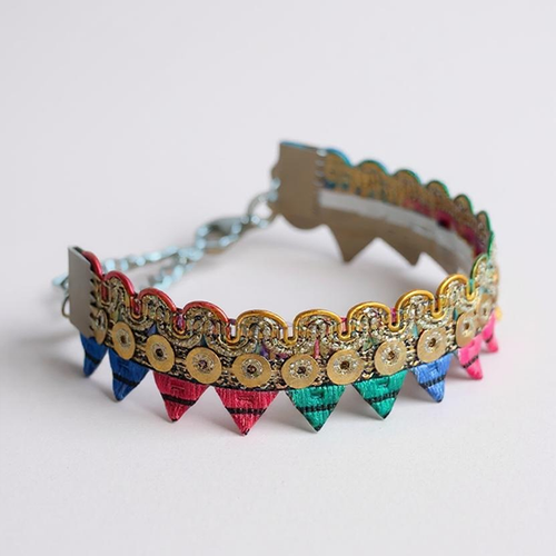 Colourful decorative bracelet with rainbow bunting and gold sequins on a plain background.