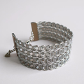 Wide silver sequin bracelet on a plain background.