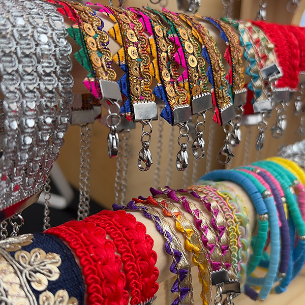 Colourful sari fabric bracelets of various designs on a wooden display stand.